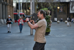 Man filming on a busy city street.